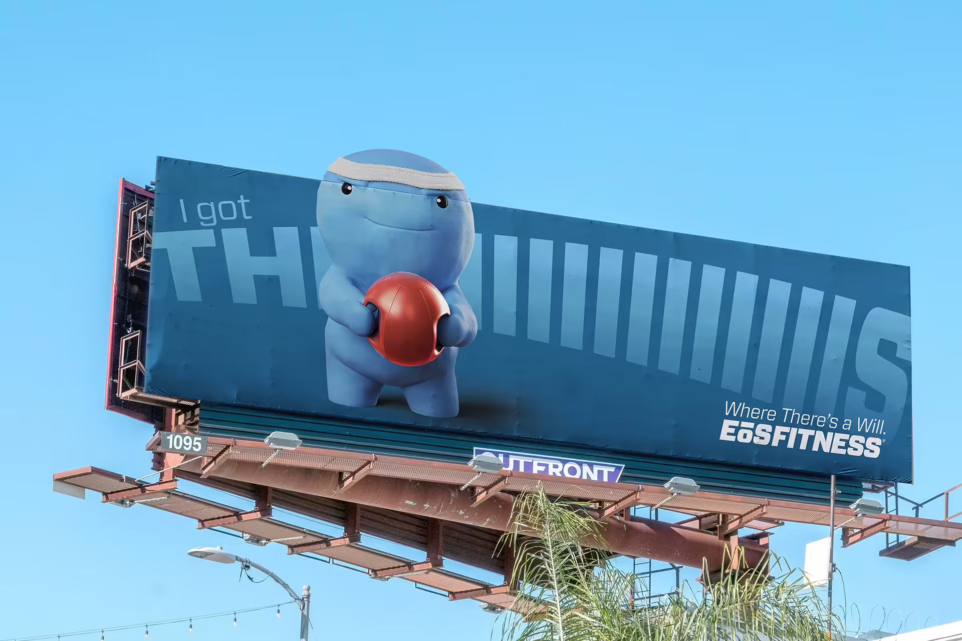 A billboard above the trees, with an image of Will Power lifting a red weight on a blue background.