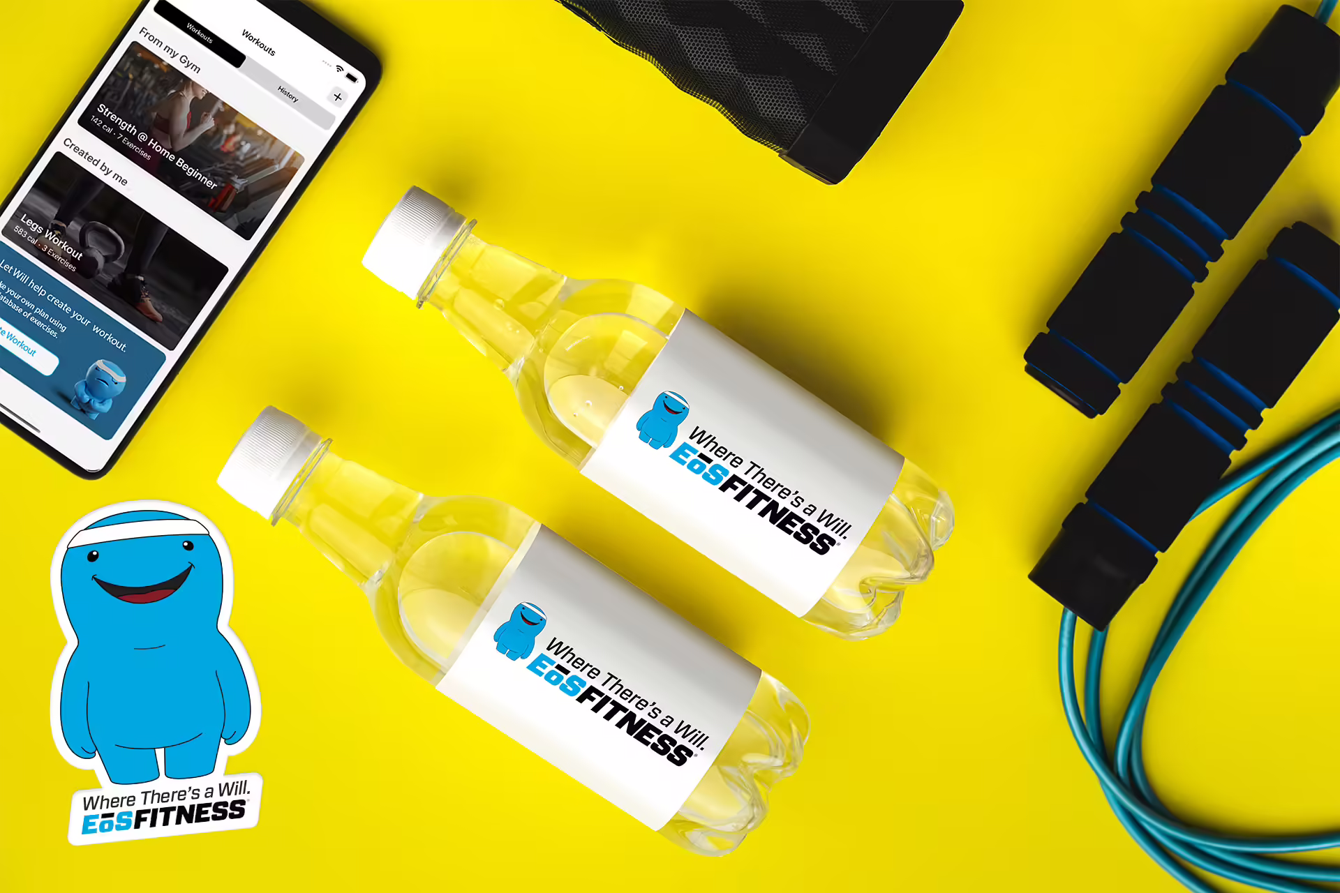 EOS promotional items on a yellow desktop, including a speaker, an EOS sticker, water bottles, a jump rope and a phone displaying the EOS mobile website.