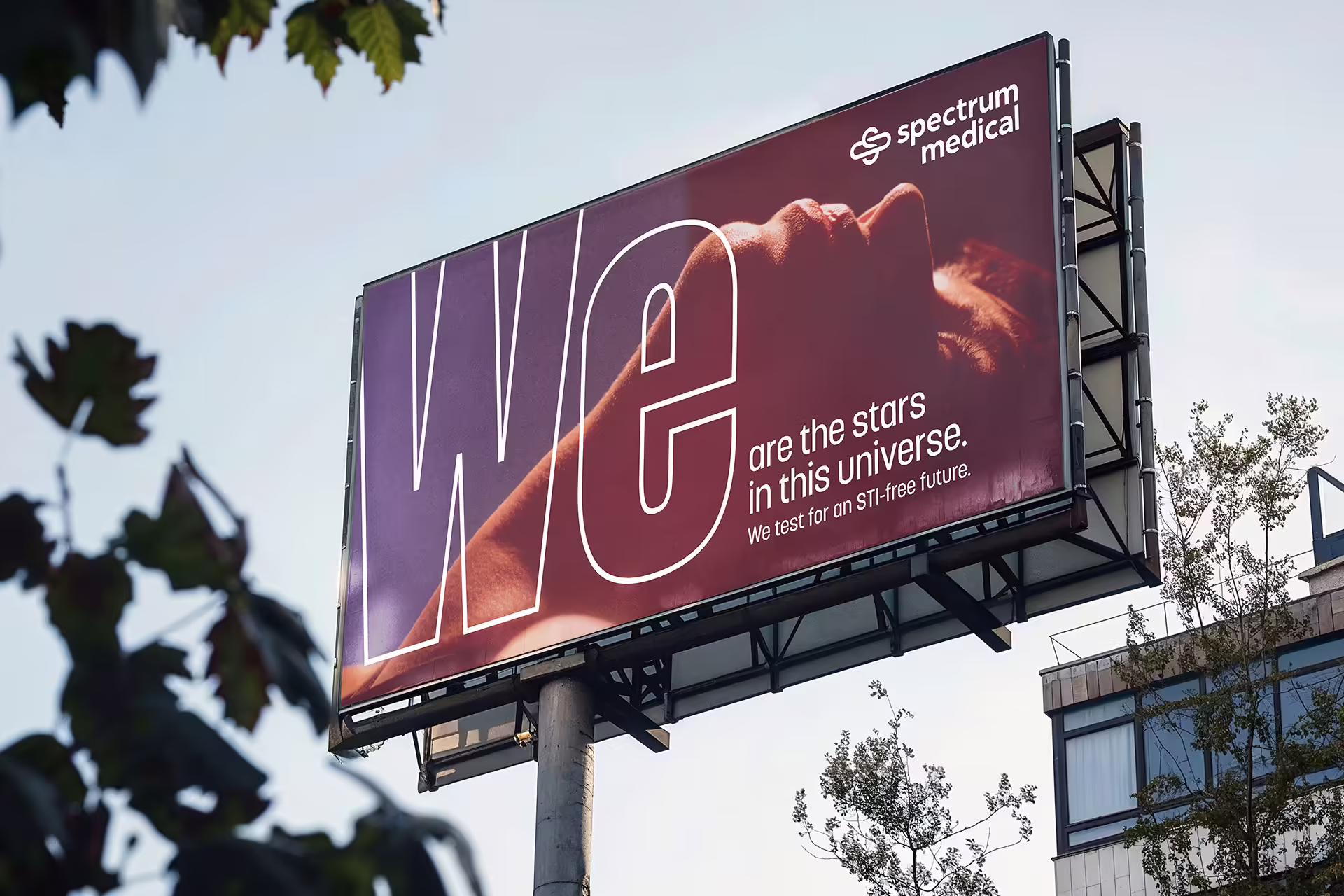 A billboard above the trees, with an image of a person laying back looking upward.